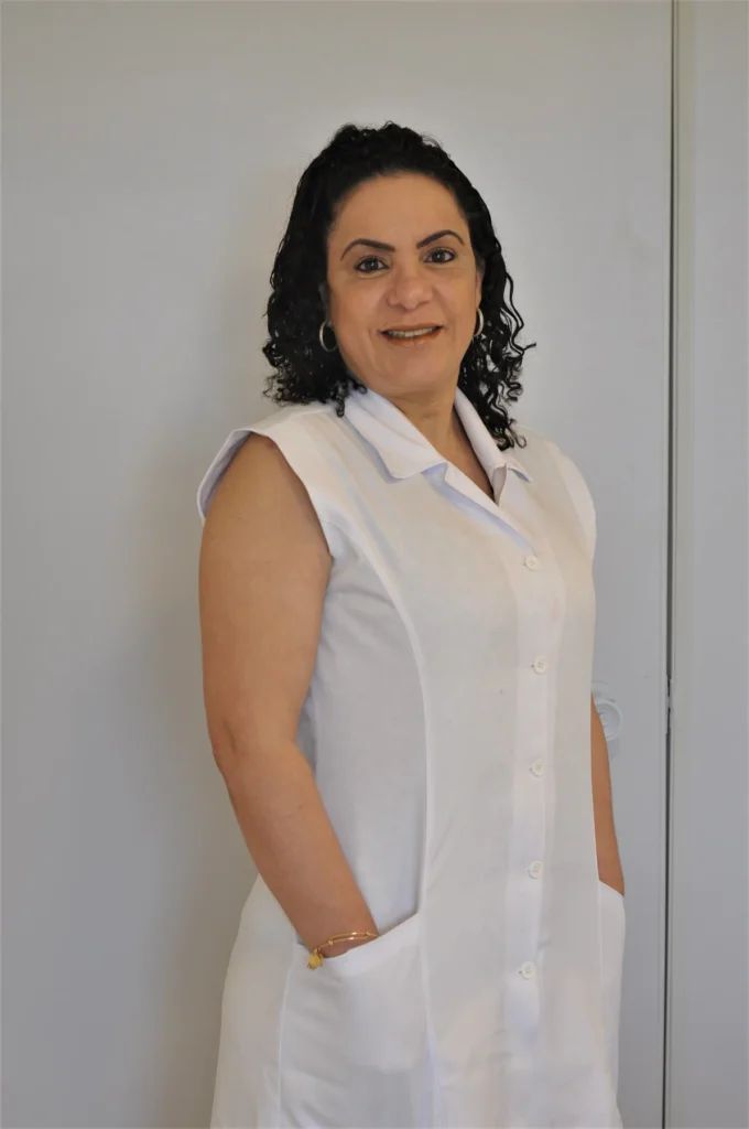 Dra. Denise Lopes em retrato com uniforme branco, de pé