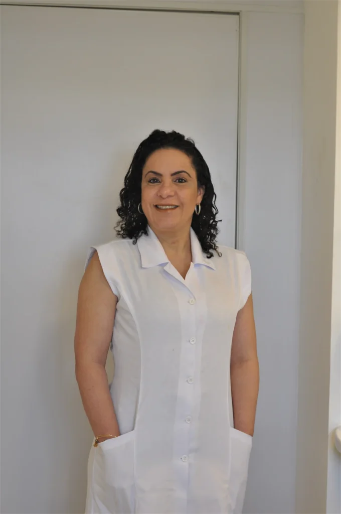 Dra. Denise Lopes sorrindo, em retrato profissional com uniforme branco